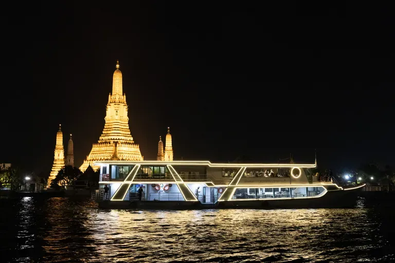 Shangri-La Horizon dinner cruise lit up at night in front of Wat Arun on the Chao Phraya River